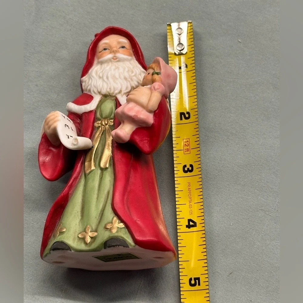 Small porcelain Santa figure.Santa carries a doll and a copy of his list.